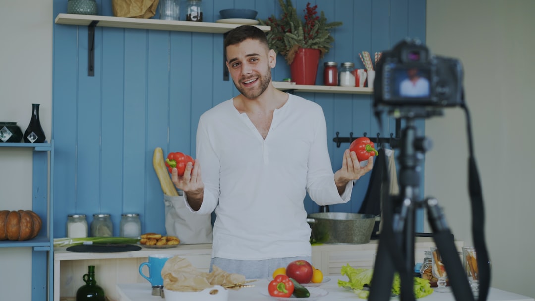 client-satisfaction-img Attractive cheerful man recording video food blog about cooking on dslr camera in kitchen at home